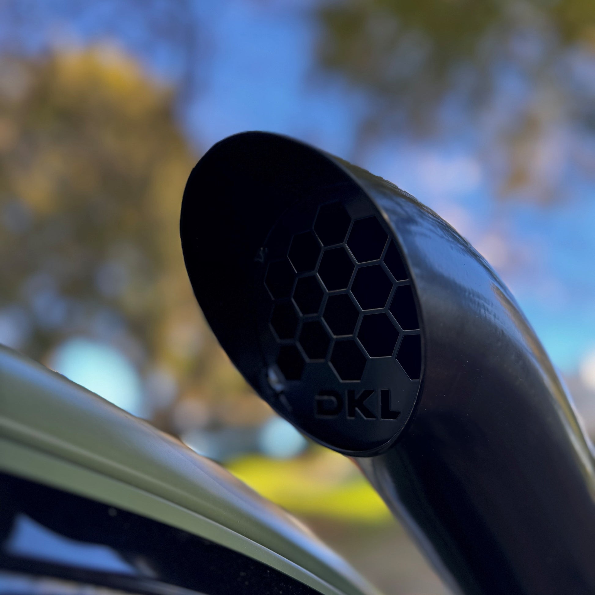 Close-up of a car exhaust tip with a blurred natural background.